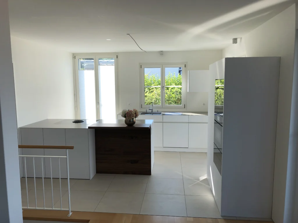 Weisse Küche mit Halbinsel und Fenstern zum Garten