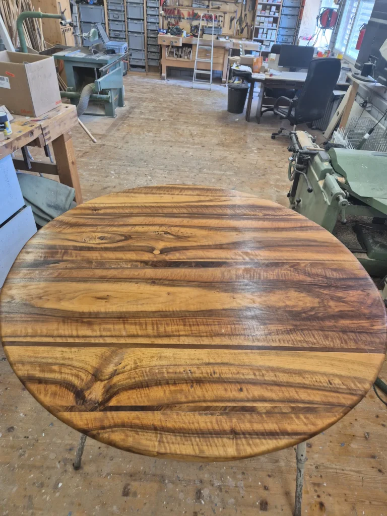 Runde Tischplatte aus stark gemasertem Holz in der Werkstatt